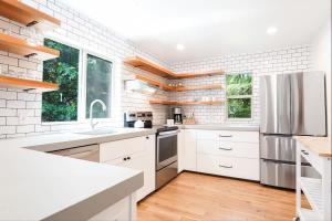 a kitchen with white cabinets and a stainless steel refrigerator at Wandering Rivers Retreat in Glacier