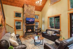 a living room with leather furniture and a stone fireplace at Cottonwood Cabin in Glacier