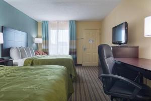 a hotel room with two beds and a desk and a television at Quality Inn Calhoun North I-75 in Calhoun