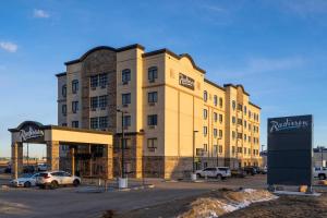 a large building with cars parked in a parking lot at Radisson Hotel Edmonton Airport in Leduc