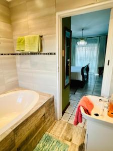 a bathroom with a bath tub and a bedroom at Emangwaneni Guest House in Kloof +29 photos