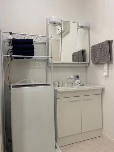 a white bathroom with a sink and a mirror at House Nozomi in Kyoto +70 photos