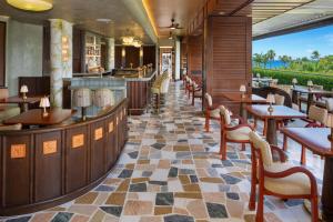 a restaurant with a bar and tables and chairs at Ka Laʻi Waikiki Beach, LXR Hotels & Resorts in Honolulu