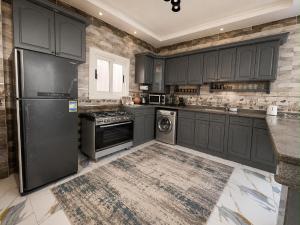 a kitchen with black cabinets and a refrigerator at Nubian Villa with Private Pool in Naj‘ al Aḩwāl
