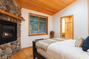 a bedroom with a stone fireplace and a bed at Snowline Hillside Chalet in Glacier +38 photos
