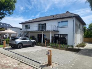 a silver car parked in front of a white house at Haus Eintracht Appartment 3 in Sankt Peter-Ording