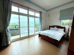 a bedroom with a bed and a large window at 花蓮統一的家民宿The home place in Ji'an
