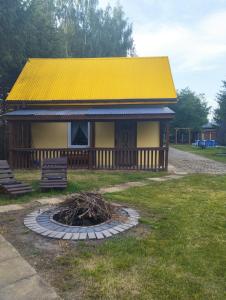 a yellow house with a yellow roof and a fire pit at Domki pod brzózkami in Bodzentyn