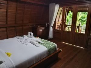 a bedroom with a bed with white towels on it at Kawandini Homestay in Sidemen