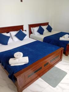 two beds in a room with towels on them at Seven Crest Hotel Anuradhapura in Anuradhapura