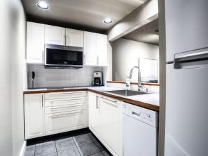 a white kitchen with a sink and a microwave at Snowater Respite in Glacier