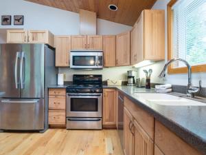 a kitchen with stainless steel appliances and wooden cabinets at Woodland Bungalow in Glacier
