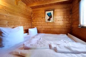 a bedroom with a white bed in a wooden room at Ferienwohnung Reimann in Loddin