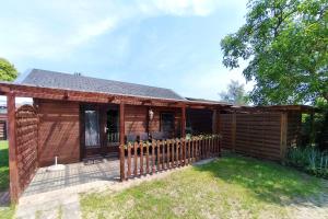 a wooden cabin with a fence in the yard at Ferienwohnung Reimann in Loddin