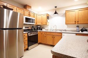 a kitchen with wooden cabinets and a stainless steel refrigerator at Yverin Muse Cabin in Glacier +30 photos