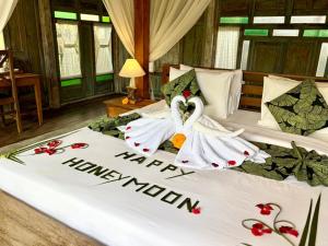 two swans dressed in towels are sitting on a bed at Sarini Joglo Villa by Manara in Blahbatu +90 photos