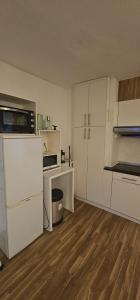 an empty kitchen with white cabinets and a desk at studio world romer in Costa da Caparica
