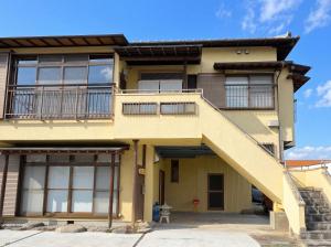 ein gelbes Haus mit einer Treppe davor in der Unterkunft かんさんのお宿 in Fuji