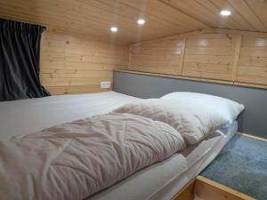 a large white bed in a room with wooden walls at Rosemont Retreat by Tiny Away in Bessé-sur-Braye