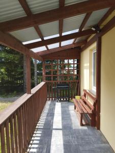 a wooden porch with a bench on a deck at Domki pod brzózkami in Bodzentyn