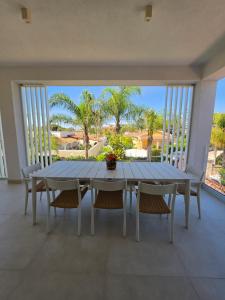 a dining room with a table and chairs and palm trees at Villa Merilusi Apartments in Fontane Bianche