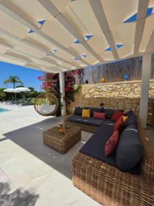 a patio with couches and chairs under a roof at Villa Merilusi Apartments in Fontane Bianche