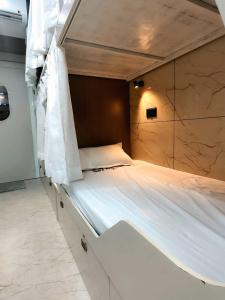 a bedroom with a large bed with white sheets at Trio Rooms & dormitory in Trivandrum