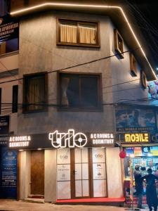 a building with a sign on the side of it at Trio Rooms & dormitory in Trivandrum