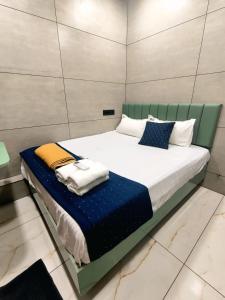 a bedroom with a large bed with blue and white pillows at Trio Rooms & dormitory in Trivandrum +3 photos