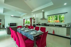 a kitchen and dining room with a table and red chairs at Chalong - 4 Bedroom Private Pool Villa - Phuket in Chalong