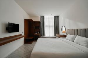 a hotel room with a bed and a television at Len Hotel in Da Lat