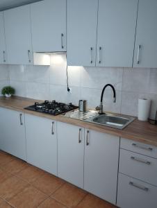 a kitchen with white cabinets and a sink at Domki pod brzózkami in Bodzentyn