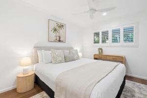 a white bedroom with a bed and two windows at Unit 6 Nirvana in Yaroomba