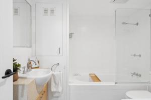 a white bathroom with a tub and a sink at Unit 6 Nirvana in Yaroomba