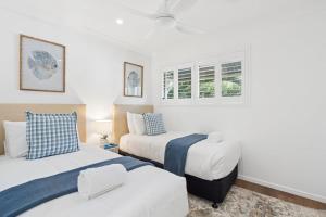 two beds in a room with white walls and windows at Unit 6 Nirvana in Yaroomba