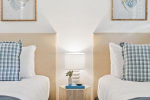a bedroom with two beds and a table with a lamp at Unit 6 Nirvana in Yaroomba +14 photos
