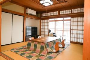 ein großer Raum mit einem Tisch und einem Wohnzimmer in der Unterkunft かんさんのお宿 in Fuji