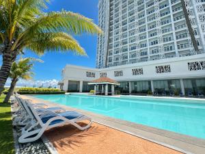 a swimming pool with lounge chairs and a building at Arterra Hotel and Resort in Mactan