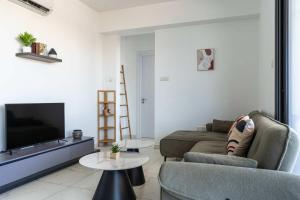 a living room with a couch and a tv at Bright Stylish Flat With Balcony & Shared Pool in Scala