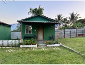 a green house with a door in a yard at Wildfarms resort in Masinagudi