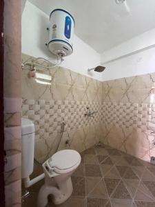 a bathroom with a toilet and a bucket on the wall at Zlatan Guest House in Leh
