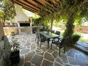 a patio with a table and chairs and a fireplace at THEODORAS HOUSE in Iraklitsa