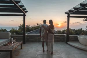 a man and woman standing on a balcony looking at the sunset at Salty Lotus in Uluwatu