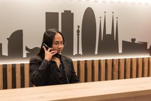 a woman sitting at a table talking on a cell phone at May Ramblas Hotel in Barcelona