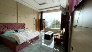 a bedroom with a bed and a large window at devdaar hills homes cafe & resort in Mussoorie