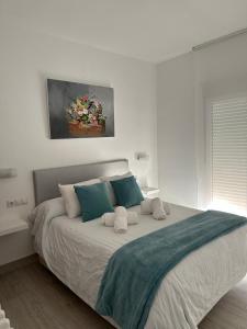 a white bedroom with a large bed with blue pillows at CASA MARUJA in Ávila