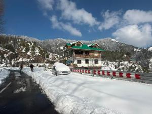 a house in the snow with cars parked on the road at Himalyan Kitchen & Stay in Matiāna +11 photos