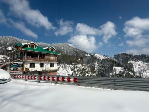 a building in the snow next to a mountain at Himalyan Kitchen & Stay in Matiāna