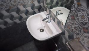 a white sink in a bathroom with a tile wall at Hotel Ganga Ram in Chitrakoot