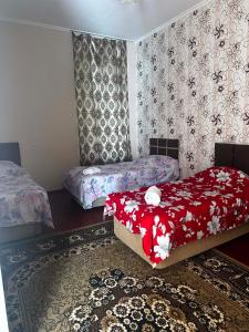 a bedroom with two beds with red blankets and a rug at Guest hous Tamuna in Martvili